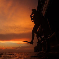 night-diver-jumping-big-step-out-of-the-diving-boat-sunset