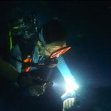 night-diver-checking-his-dive-computer-with-torch-lamp